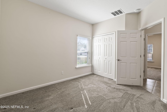 unfurnished bedroom featuring multiple windows, a closet, and light carpet