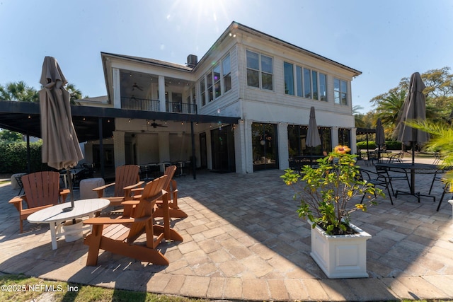 rear view of property featuring ceiling fan and a patio area