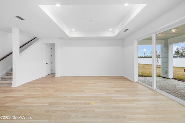 empty room featuring crown molding, a raised ceiling, and light hardwood / wood-style flooring