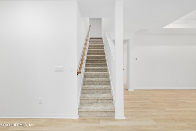 staircase featuring hardwood / wood-style floors and crown molding