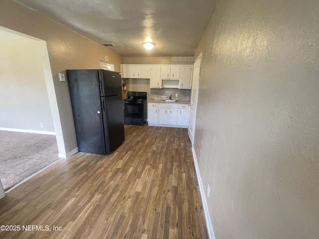 kitchen with black appliances, hardwood / wood-style flooring, white cabinetry, and sink