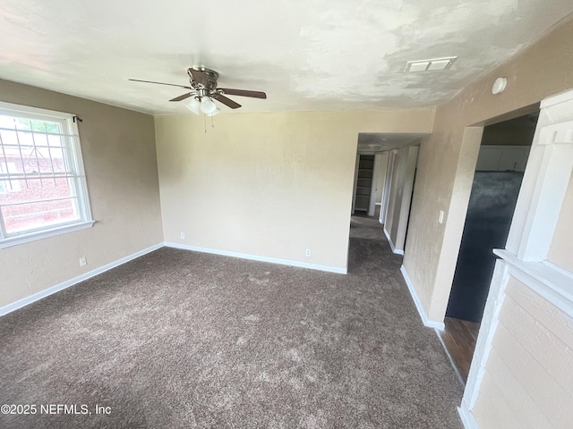 spare room with ceiling fan and dark colored carpet