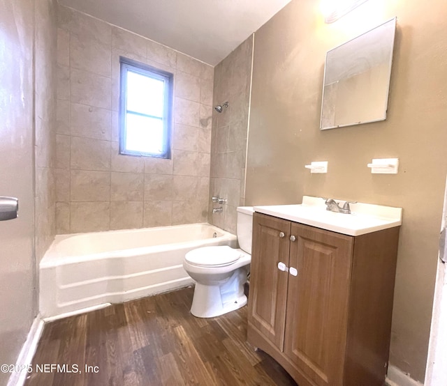 full bathroom featuring wood-type flooring, toilet, tiled shower / bath combo, and vanity