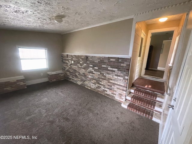 carpeted spare room with brick wall and a textured ceiling