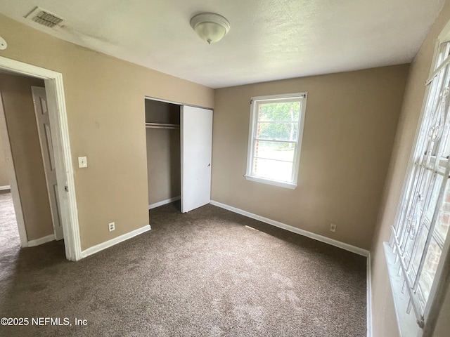 unfurnished bedroom with a closet and dark carpet