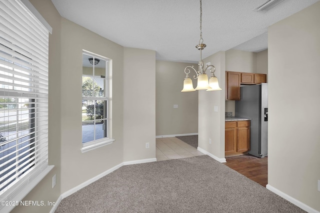 unfurnished dining area featuring lofted ceiling, carpet, a textured ceiling, and an inviting chandelier