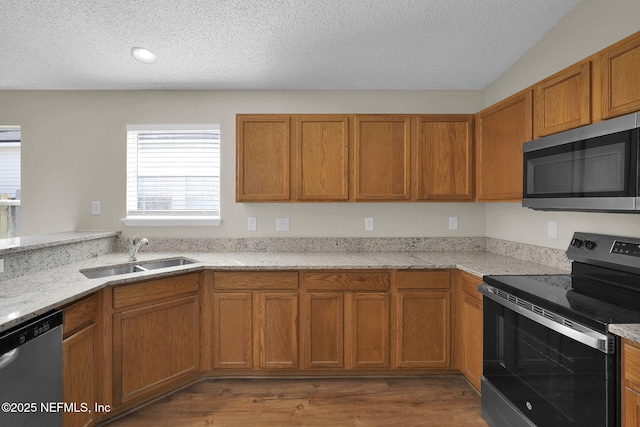 kitchen featuring light stone counters, stainless steel appliances, sink, and hardwood / wood-style floors