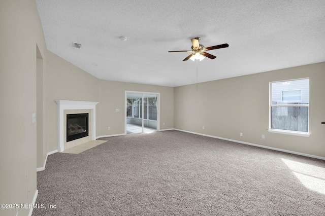 unfurnished living room featuring a textured ceiling, a fireplace, light colored carpet, and ceiling fan