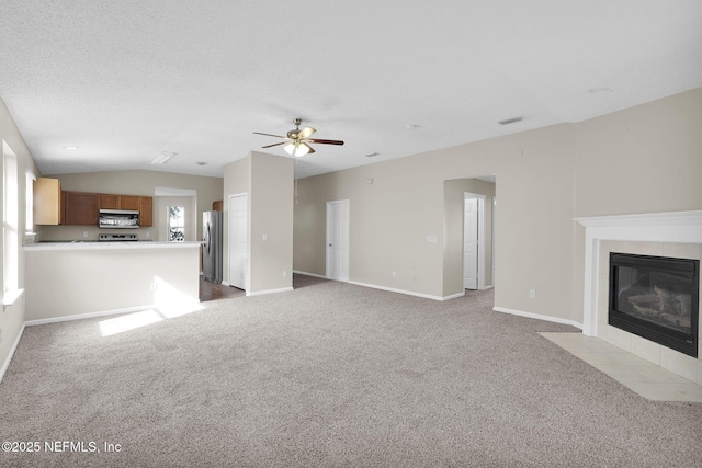 unfurnished living room with lofted ceiling, ceiling fan, a fireplace, a textured ceiling, and light colored carpet