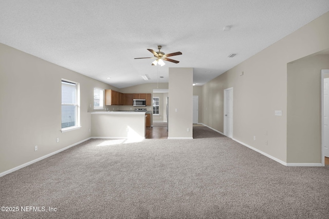 unfurnished living room with vaulted ceiling, carpet floors, a textured ceiling, and ceiling fan