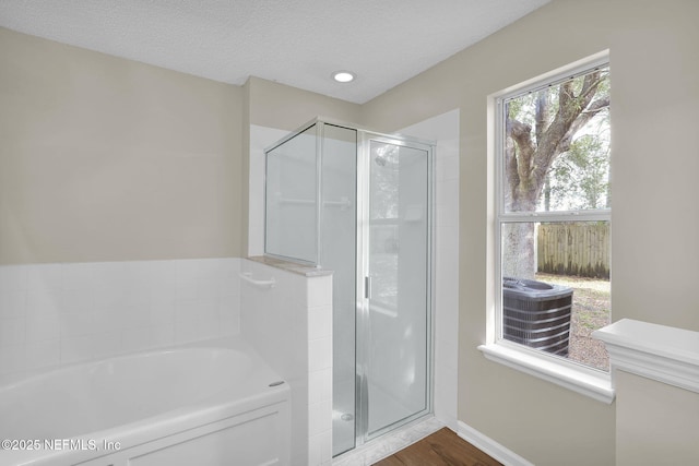 bathroom featuring hardwood / wood-style flooring, plus walk in shower, and a textured ceiling