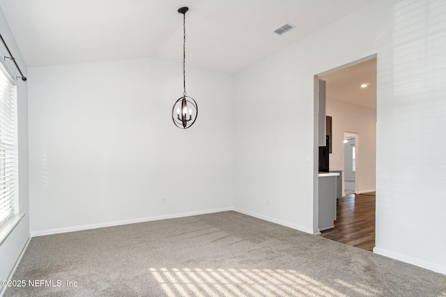 empty room with dark colored carpet, vaulted ceiling, plenty of natural light, and a notable chandelier