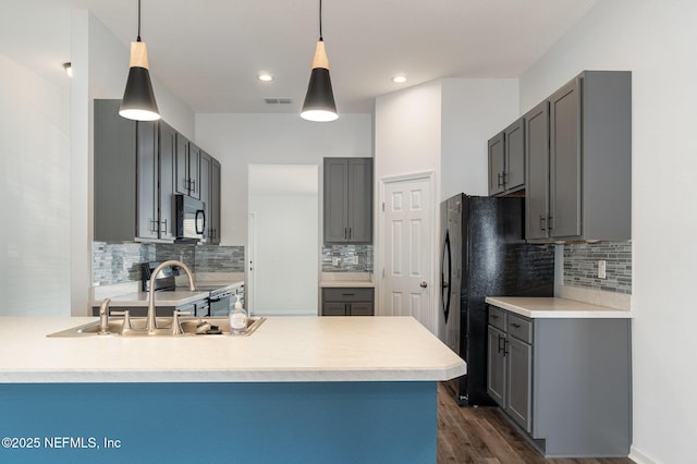 kitchen with pendant lighting, sink, black appliances, and kitchen peninsula