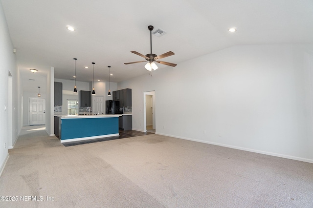 kitchen featuring lofted ceiling, ceiling fan, black refrigerator, a center island, and carpet floors