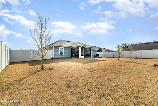 back of property with a sunroom and a lawn