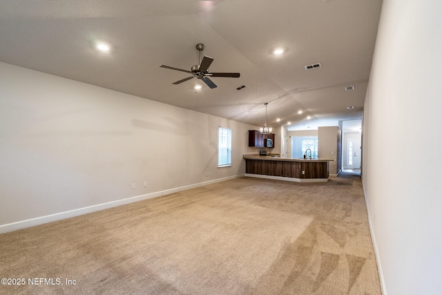 unfurnished living room featuring sink, ceiling fan with notable chandelier, light colored carpet, and lofted ceiling