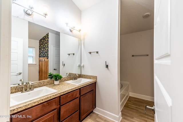 bathroom featuring hardwood / wood-style flooring, a washtub, and vanity