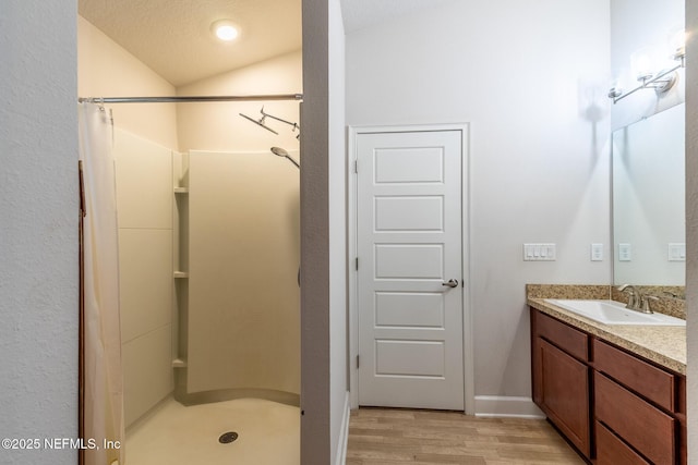 bathroom featuring hardwood / wood-style floors, a textured ceiling, curtained shower, vanity, and lofted ceiling