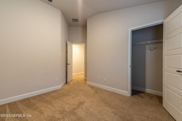 unfurnished bedroom featuring light colored carpet, a closet, and vaulted ceiling