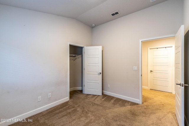 unfurnished bedroom featuring a closet, light colored carpet, and lofted ceiling