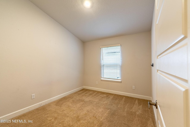 spare room featuring light carpet and vaulted ceiling