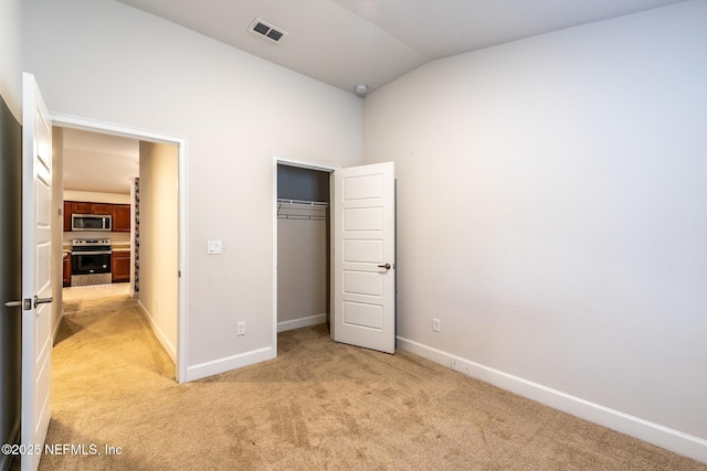 unfurnished bedroom featuring light colored carpet, a closet, and lofted ceiling