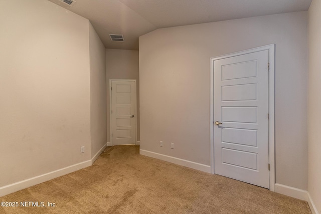 empty room featuring light colored carpet and lofted ceiling