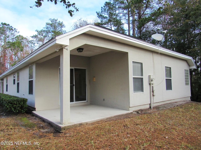 rear view of house featuring a patio area and stucco siding