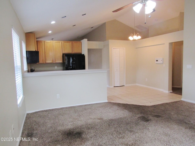 kitchen featuring light colored carpet, lofted ceiling, freestanding refrigerator, a peninsula, and light tile patterned flooring