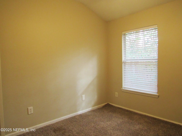 unfurnished room featuring lofted ceiling, baseboards, and dark colored carpet