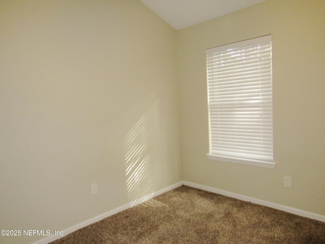 spare room featuring carpet flooring and baseboards