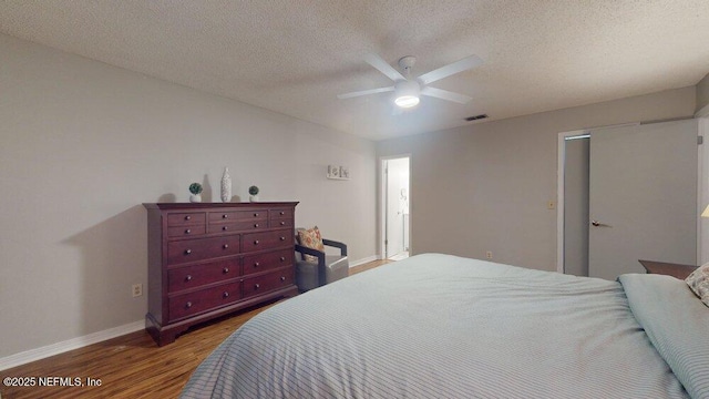 bedroom with hardwood / wood-style flooring, ceiling fan, and a textured ceiling