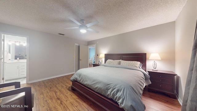 bedroom with hardwood / wood-style floors, a textured ceiling, ceiling fan, and ensuite bathroom