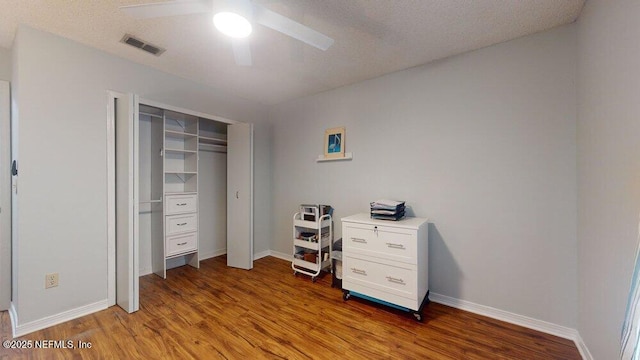 bedroom featuring ceiling fan, wood-type flooring, a closet, and a textured ceiling