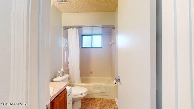 full bathroom with shower / bath combo with shower curtain, vanity, toilet, and a textured ceiling