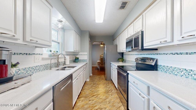 kitchen featuring sink, decorative backsplash, white cabinets, and appliances with stainless steel finishes