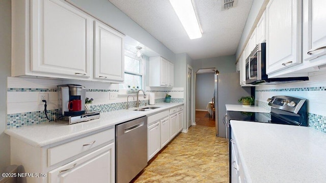 kitchen with stainless steel appliances, white cabinetry, sink, and tasteful backsplash