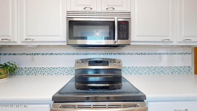 kitchen with appliances with stainless steel finishes, white cabinets, and backsplash