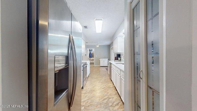 kitchen featuring stainless steel fridge, a textured ceiling, and white cabinets