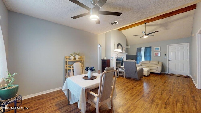 dining area with ceiling fan, vaulted ceiling with beams, hardwood / wood-style floors, and a textured ceiling