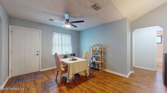 dining room with hardwood / wood-style flooring, ceiling fan, vaulted ceiling, and a textured ceiling