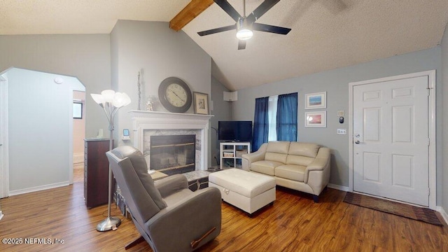 living room with hardwood / wood-style flooring, a premium fireplace, ceiling fan, high vaulted ceiling, and beamed ceiling