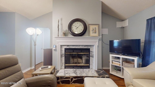 living room with wood-type flooring, a premium fireplace, vaulted ceiling, and a textured ceiling