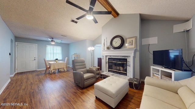 living room featuring vaulted ceiling with beams, hardwood / wood-style flooring, a premium fireplace, and a textured ceiling