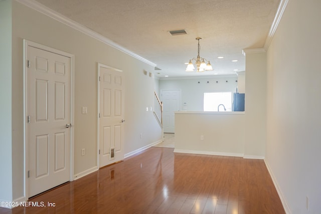 spare room featuring crown molding, light hardwood / wood-style flooring, a textured ceiling, and a chandelier