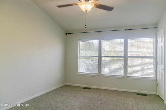 carpeted spare room with a wealth of natural light, ceiling fan, and vaulted ceiling