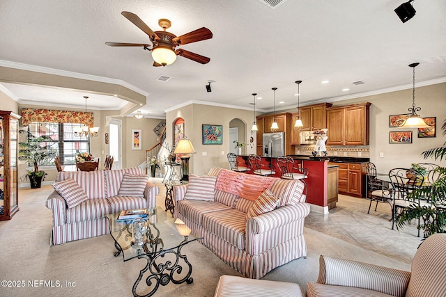 living area featuring arched walkways, ornamental molding, ceiling fan with notable chandelier, and light colored carpet