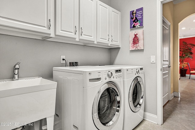 laundry area featuring cabinet space, light tile patterned floors, baseboards, washer and dryer, and a sink