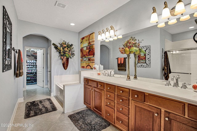 full bath with double vanity, visible vents, a garden tub, tile patterned flooring, and a sink