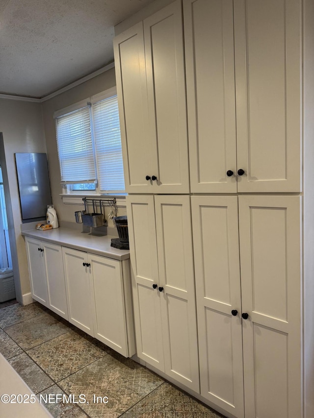 kitchen with a textured ceiling and white cabinets